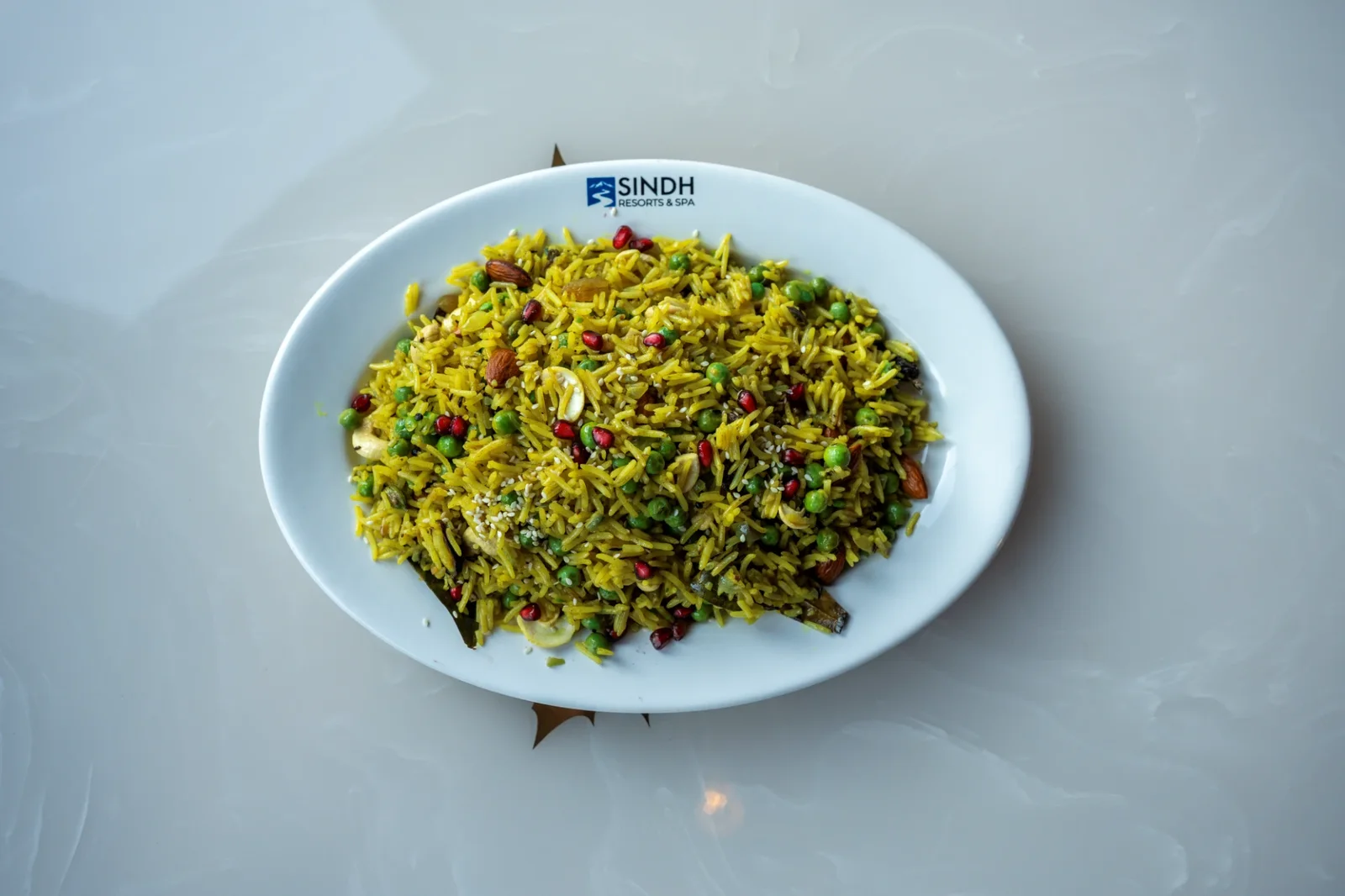 Vegetable pulao with peas, nuts and pomegranate on a Sindh Resorts plate