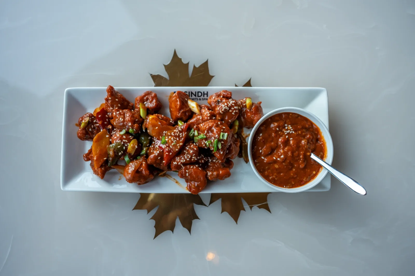 Crispy chilli starter with sesame and a dipping sauce on a Sindh Resorts plate