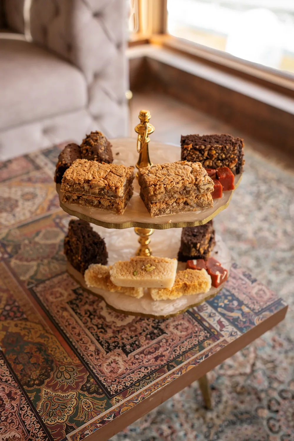 A two-tier stand of brownies, nut bars and Indian sweets